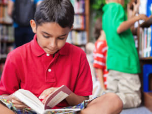Happy student reading a book in school library